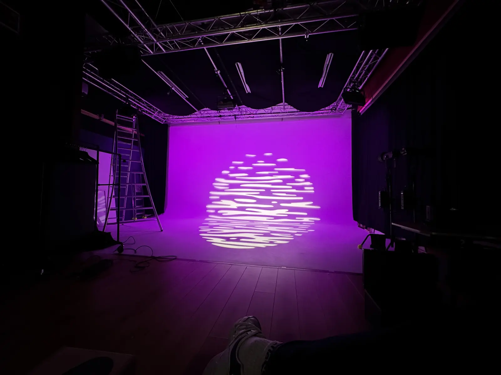 De limbo in paars licht met een gobo-patroon, vanaf achter in de studio