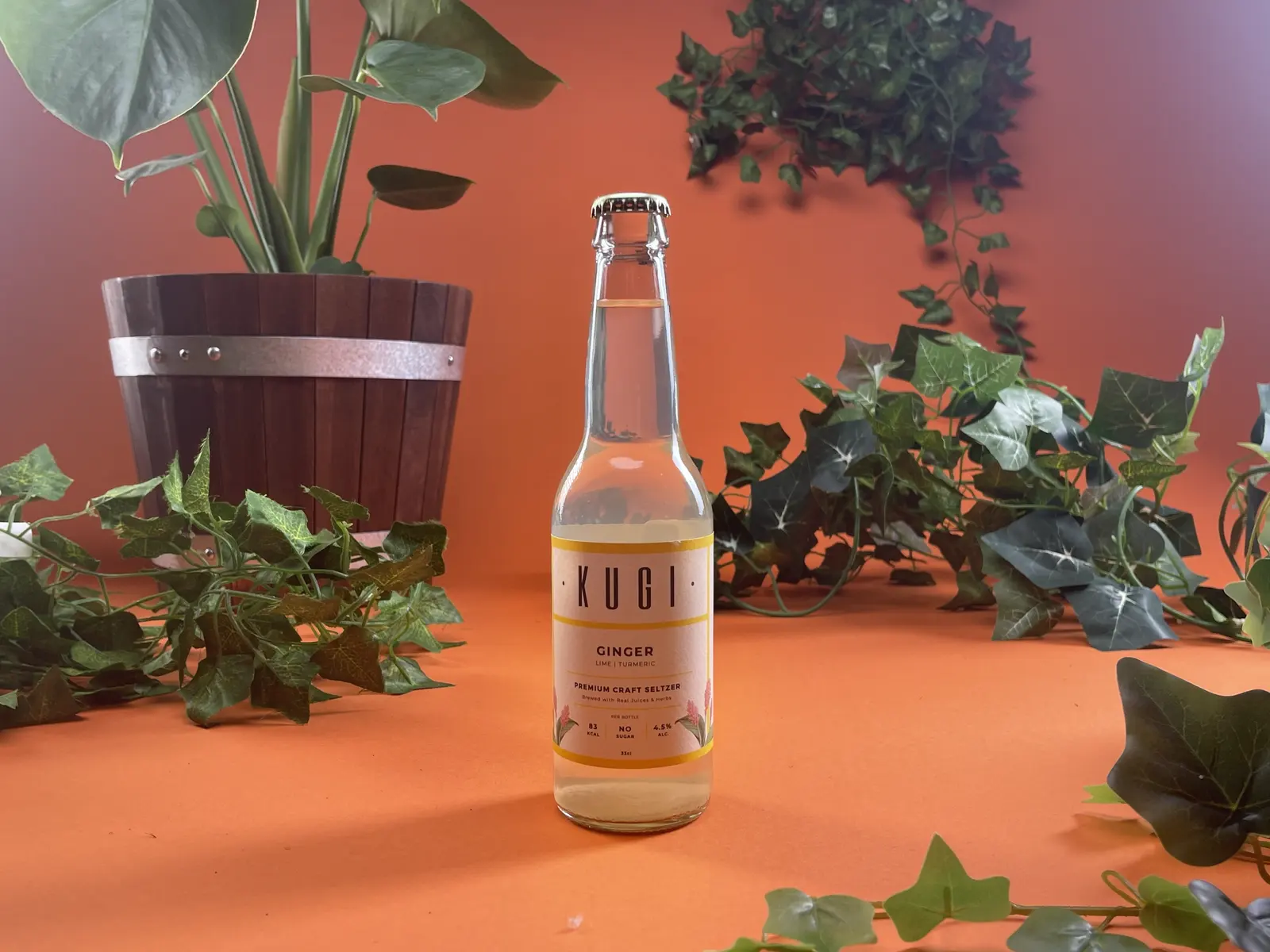 Productshot van een flesje tussen planten op een oranje achtergrond