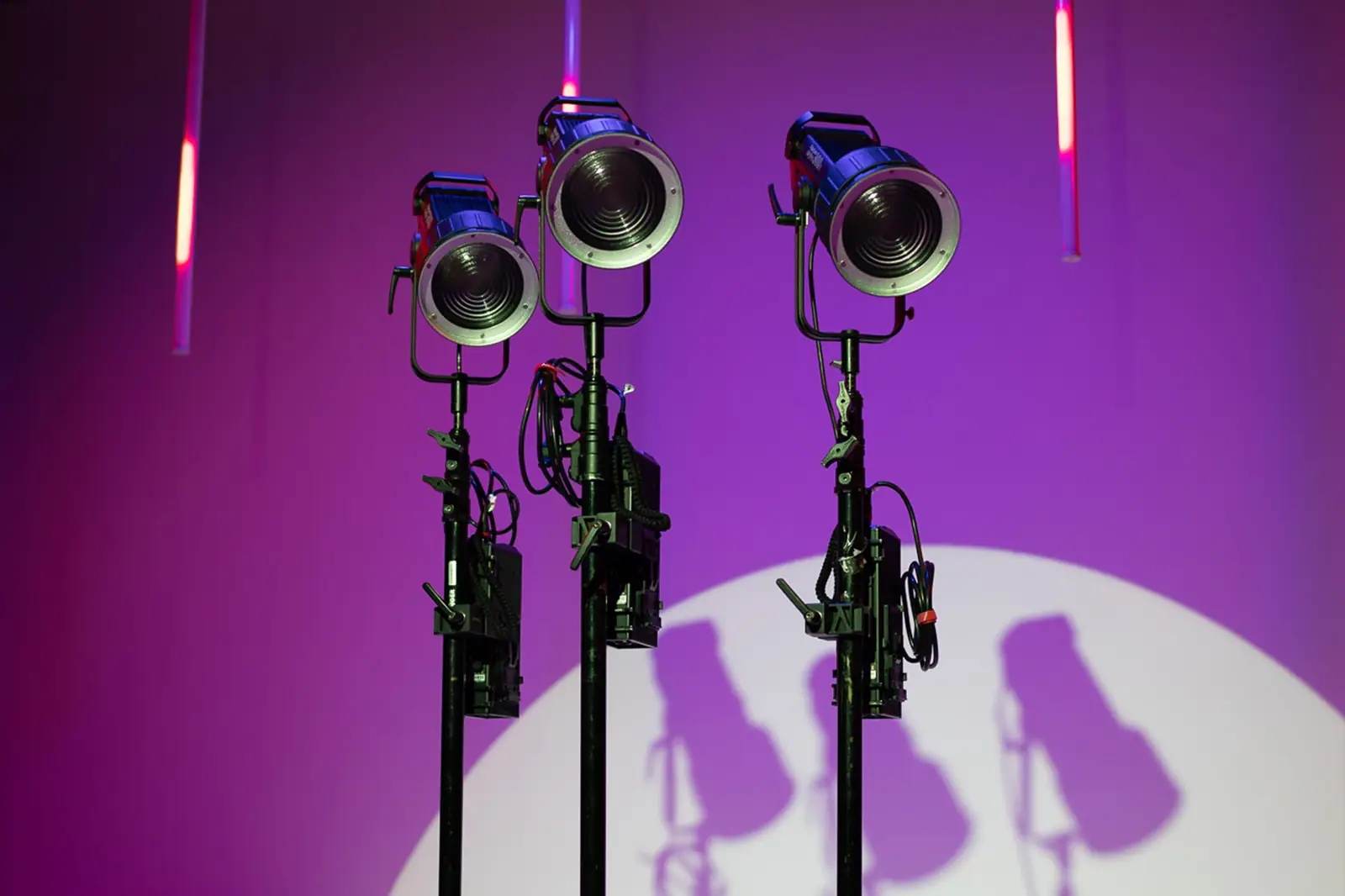 Drie fresnel-lampen op statieven in paars licht