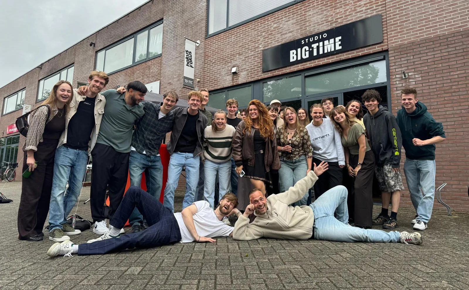 Een lachende groep mensen voor de ingang van Studio Big Time in Almere